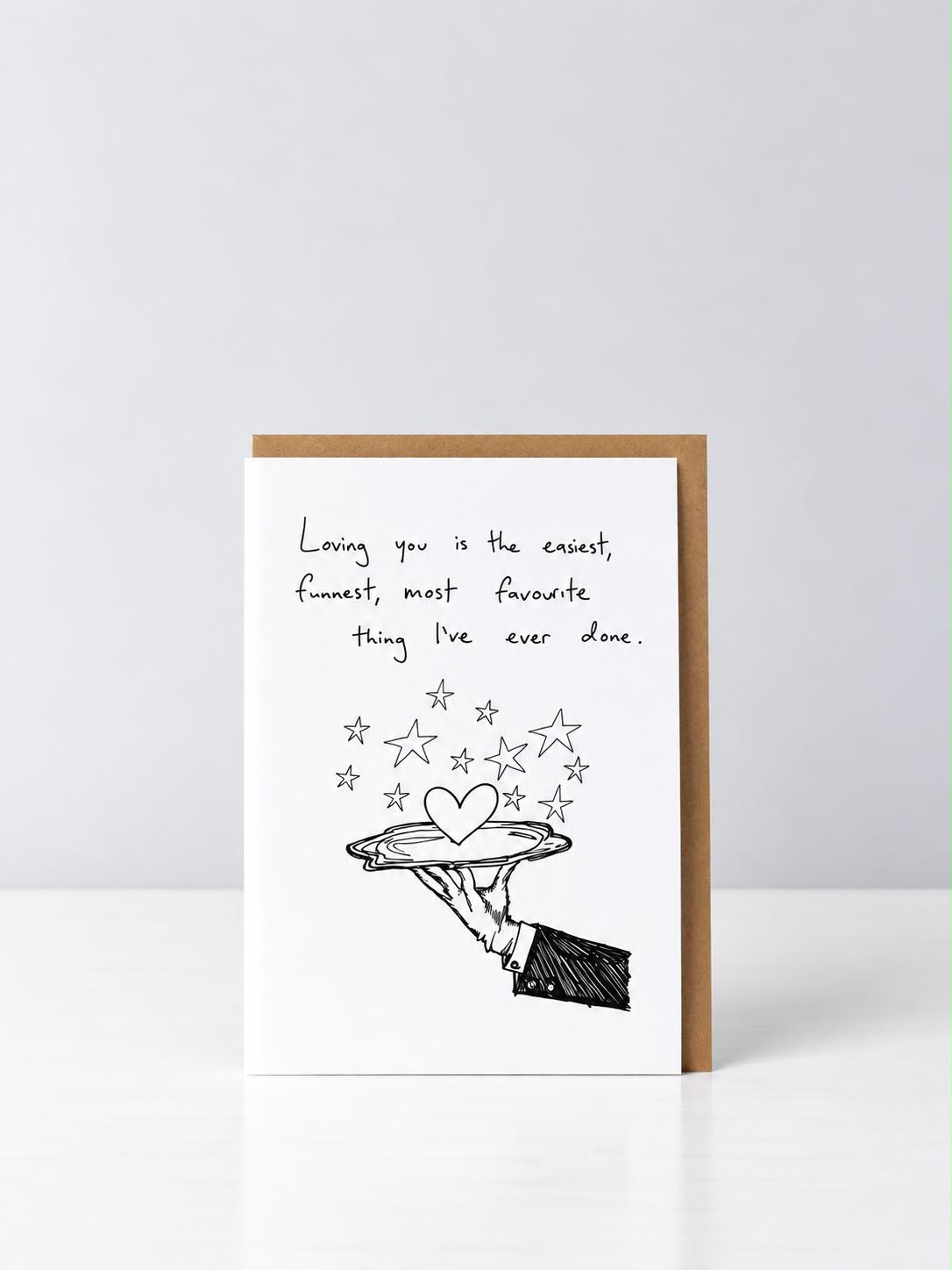 Loving You greeting card with a hand-drawn gloved hand serving a heart on a silver platter beneath stars, with a kraft envelope