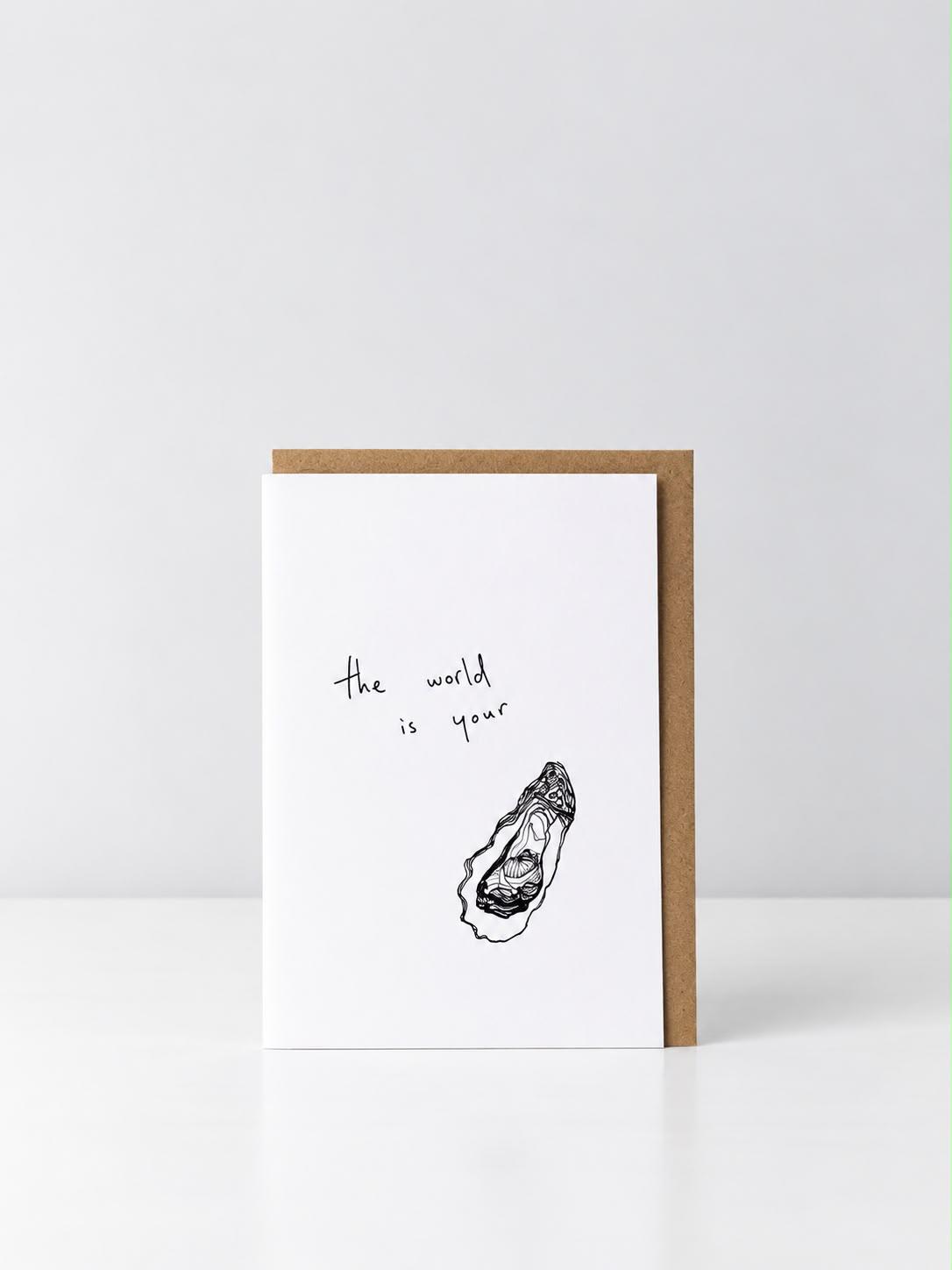 See Aiche greeting card reading “the world is your” above a hand-drawn oyster, with a kraft envelope